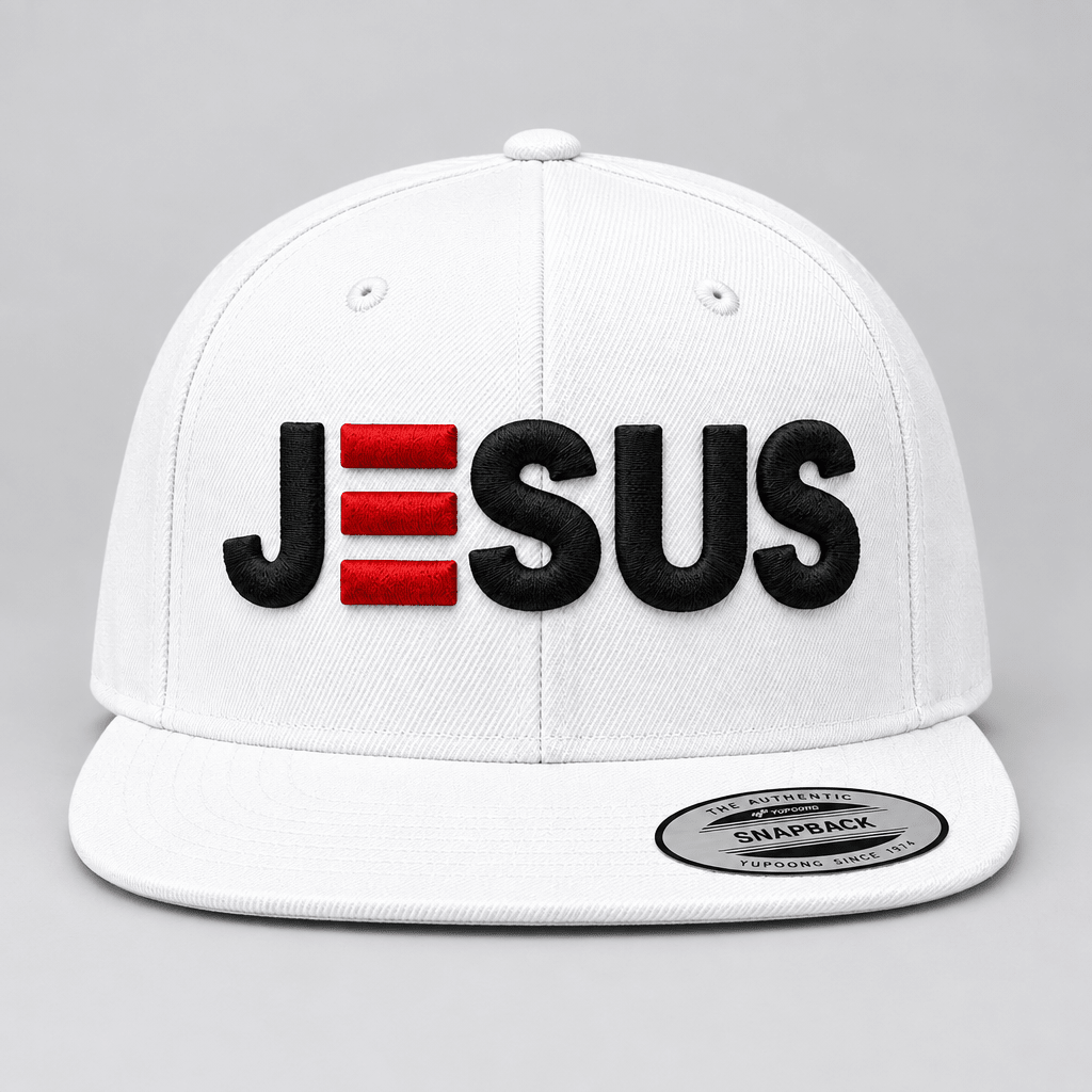 A white snapback cap featuring the word 'JESUS' embroidered on the front, with the letter 'E' represented by three red rectangular bars. A silver and black Snapback sticker is visible on the brim.